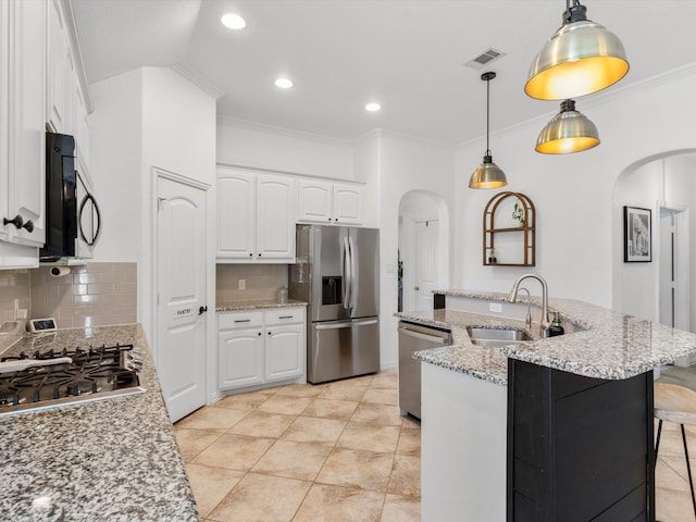 kitchen with visible vents, a kitchen island with sink, arched walkways, a sink, and stainless steel appliances