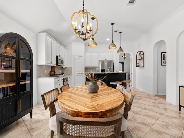 dining space with arched walkways, light tile patterned floors, a notable chandelier, and vaulted ceiling