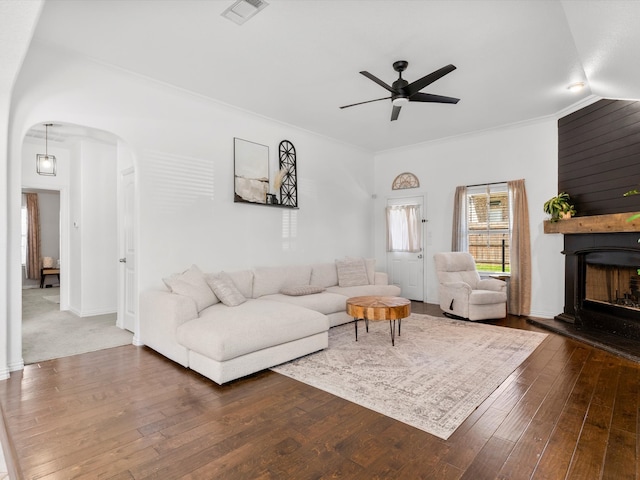 living area featuring visible vents, arched walkways, dark wood-type flooring, and a fireplace