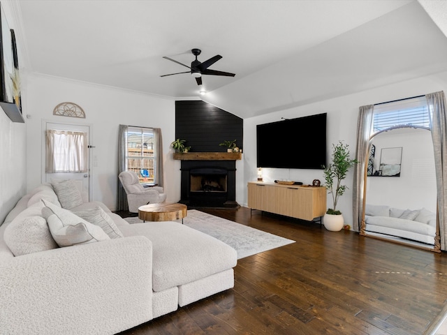 living area with a large fireplace, ceiling fan, vaulted ceiling, ornamental molding, and dark wood-style flooring