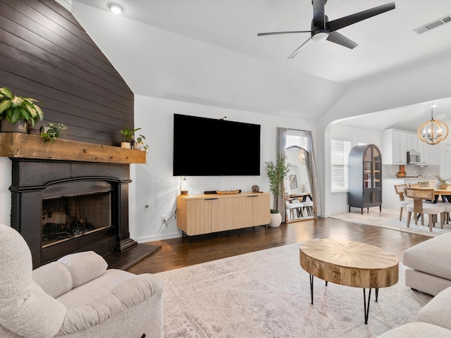 living room with visible vents, wood finished floors, a large fireplace, arched walkways, and vaulted ceiling