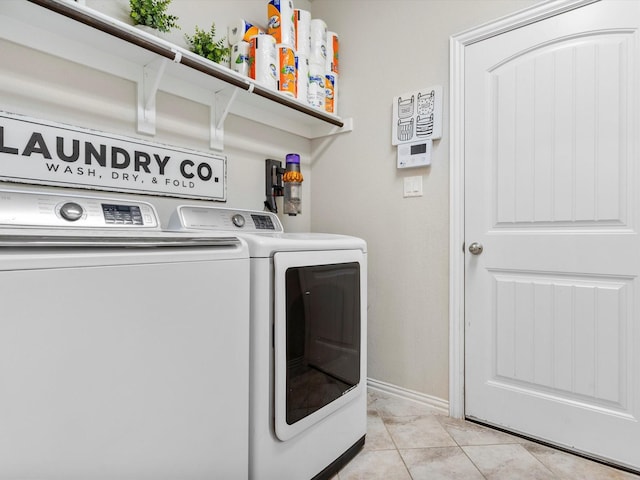 laundry area with washing machine and clothes dryer, laundry area, baseboards, and light tile patterned flooring