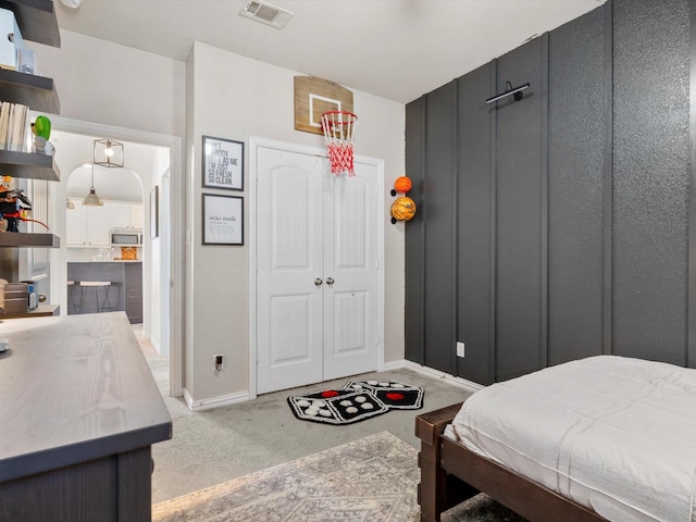 carpeted bedroom with arched walkways, visible vents, a closet, and baseboards