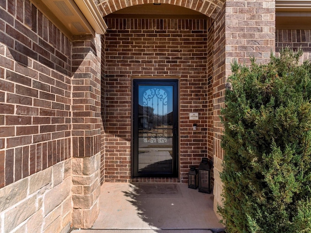 doorway to property featuring brick siding