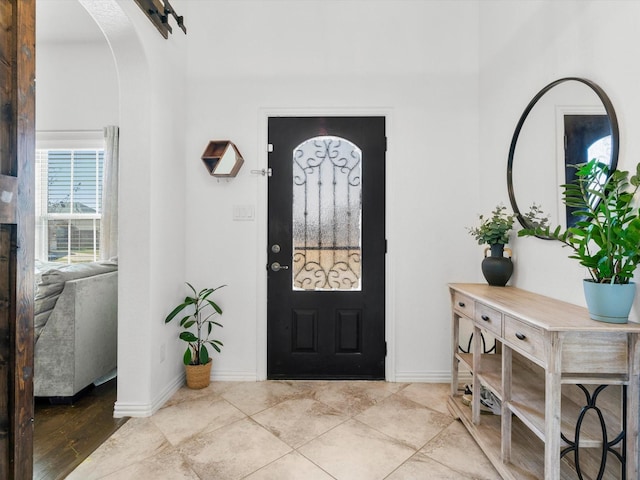 foyer featuring baseboards and arched walkways