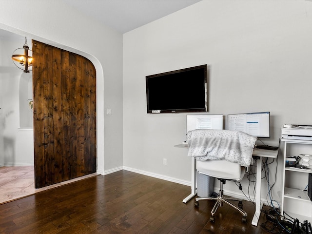 home office with arched walkways, baseboards, and hardwood / wood-style floors