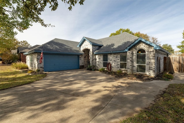 view of front facade featuring fence, driveway, roof with shingles, an attached garage, and brick siding