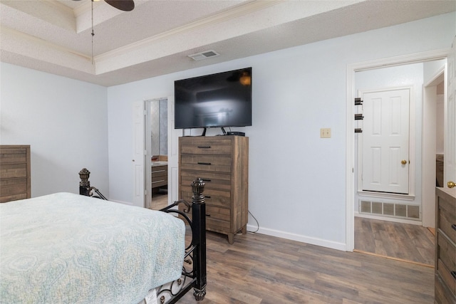 bedroom with visible vents, a textured ceiling, baseboards, and wood finished floors