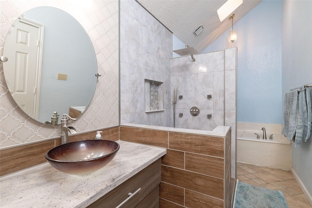 bathroom featuring a walk in shower, vanity, a garden tub, vaulted ceiling with skylight, and a textured ceiling