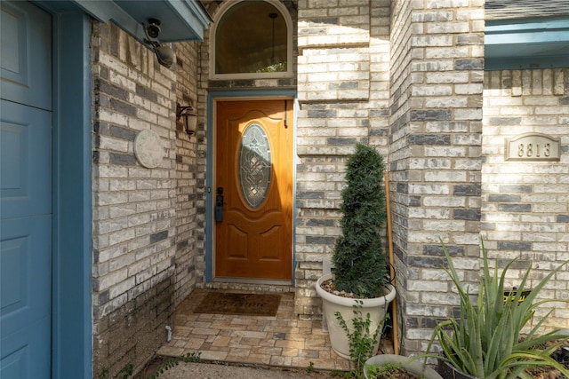 property entrance featuring a garage and brick siding