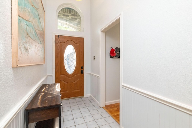 foyer entrance with light tile patterned floors and a wainscoted wall