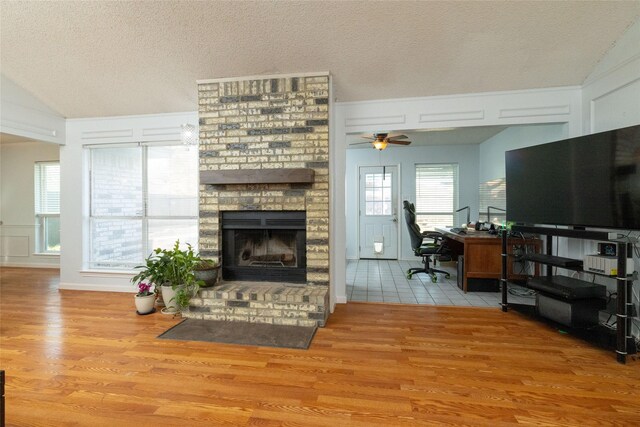 living area featuring a decorative wall, a fireplace, a textured ceiling, and wood finished floors