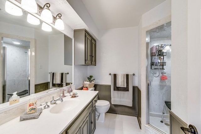 bathroom featuring tile patterned floors, toilet, a stall shower, and vanity