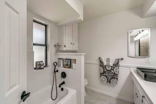 bathroom featuring vanity, a tub, wainscoting, toilet, and marble finish floor