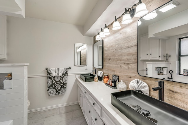 bathroom with double vanity, wood walls, and a sink