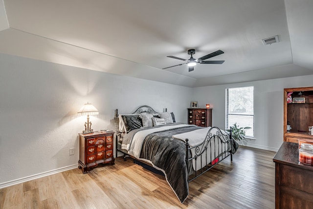 bedroom with light wood finished floors, visible vents, baseboards, and vaulted ceiling