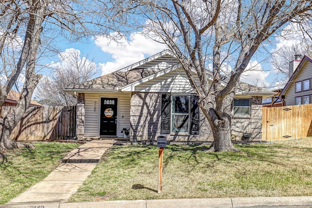 bungalow-style home featuring a front lawn and fence