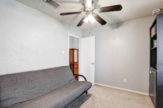 living area featuring baseboards, visible vents, a textured ceiling, and carpet