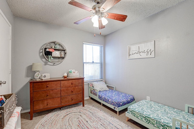 carpeted bedroom featuring ceiling fan, a textured ceiling, and baseboards