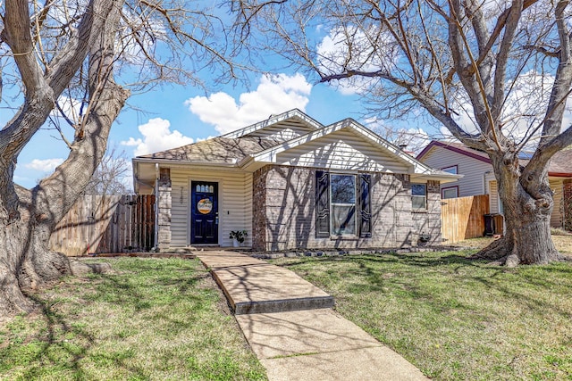 view of front of home featuring a front lawn, fence, and brick siding