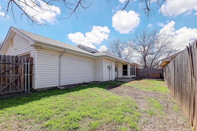 rear view of house with a yard and a fenced backyard