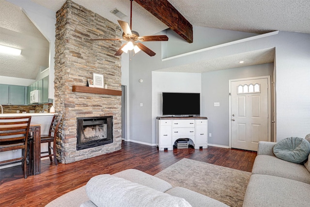 living room featuring a stone fireplace, wood finished floors, visible vents, and a textured ceiling