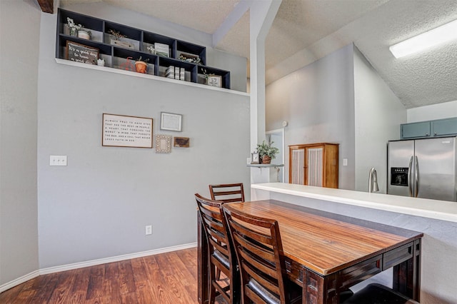 dining space with a textured ceiling, baseboards, and wood finished floors