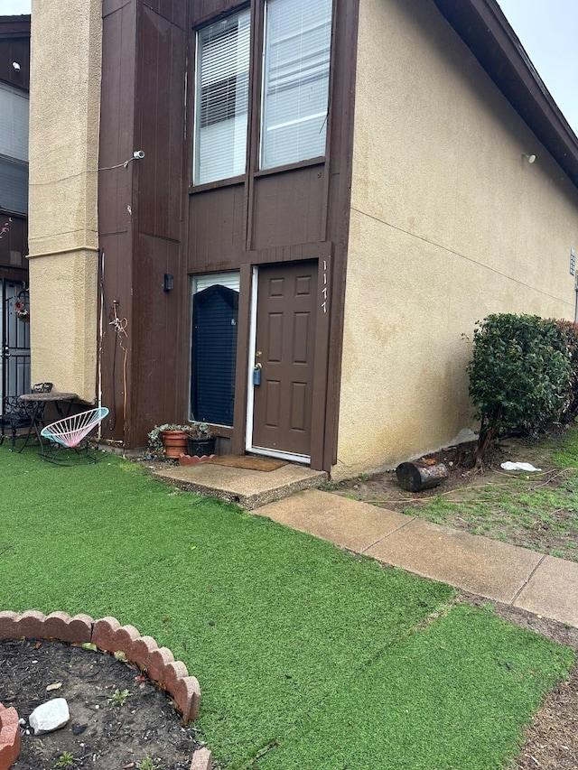 entrance to property with a yard and stucco siding