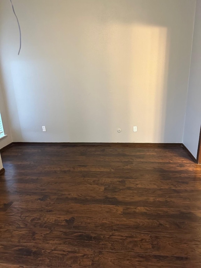 empty room with baseboards and dark wood-style flooring