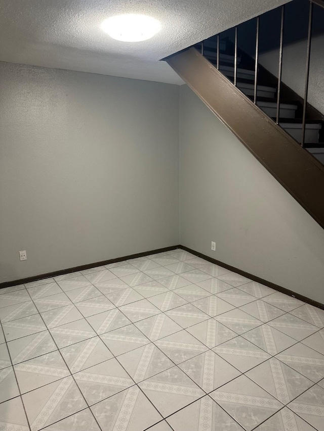 interior space featuring light tile patterned floors, stairway, a textured ceiling, and baseboards