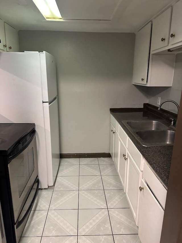 kitchen featuring dark countertops, baseboards, light tile patterned floors, electric range, and a sink