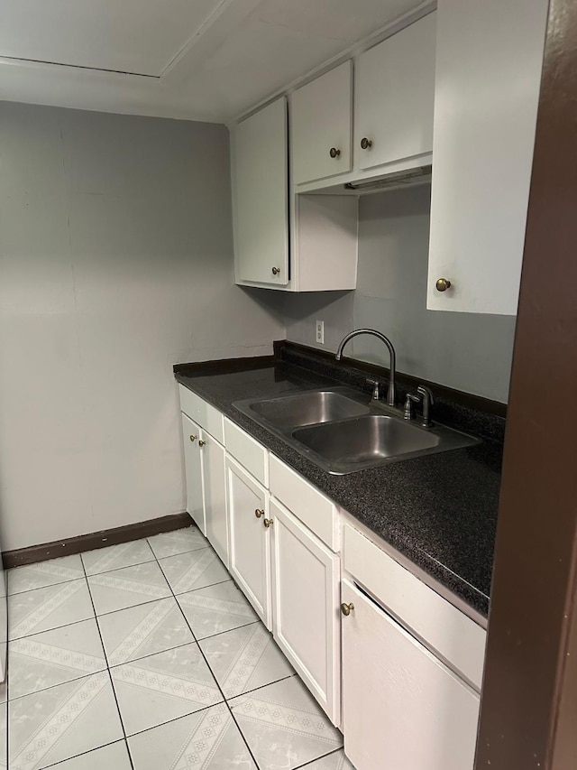 kitchen featuring light tile patterned floors, dark countertops, baseboards, and a sink