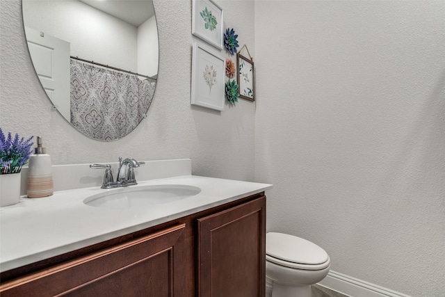 full bath featuring a shower with curtain, toilet, vanity, and a textured wall