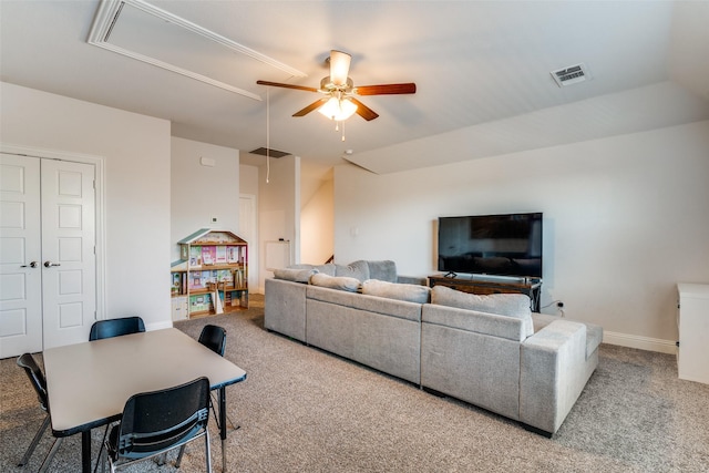 carpeted living area with ceiling fan, attic access, baseboards, and visible vents