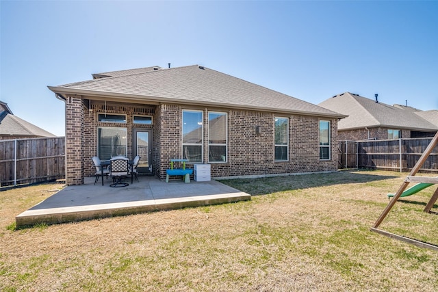 rear view of house featuring a yard, brick siding, and a fenced backyard