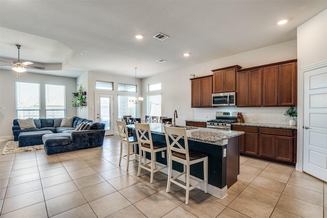 kitchen with a kitchen bar, visible vents, a sink, backsplash, and stainless steel appliances