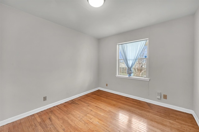 spare room with baseboards and light wood-style floors