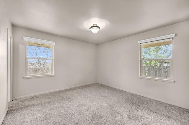 carpeted spare room with baseboards and a wealth of natural light