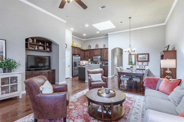 living room featuring wood finished floors, baseboards, visible vents, a high ceiling, and ornamental molding