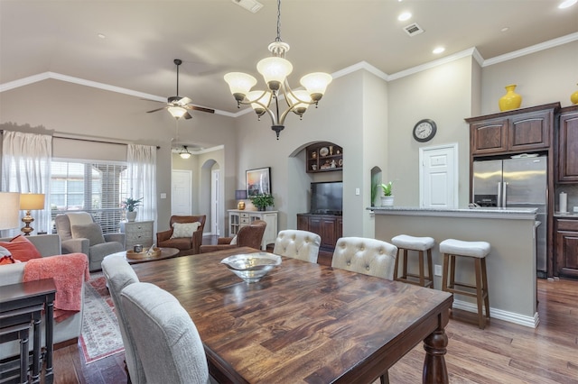 dining area featuring visible vents, high vaulted ceiling, arched walkways, ornamental molding, and light wood-type flooring