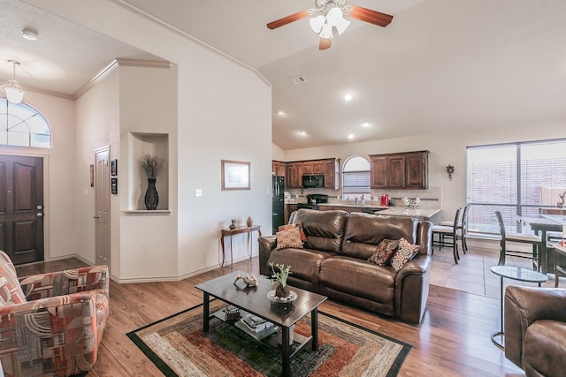 living room with light wood finished floors, ceiling fan, baseboards, ornamental molding, and high vaulted ceiling