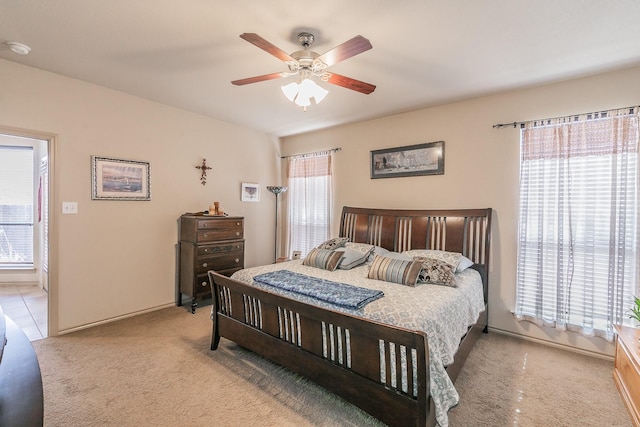 bedroom featuring ceiling fan, multiple windows, and light carpet