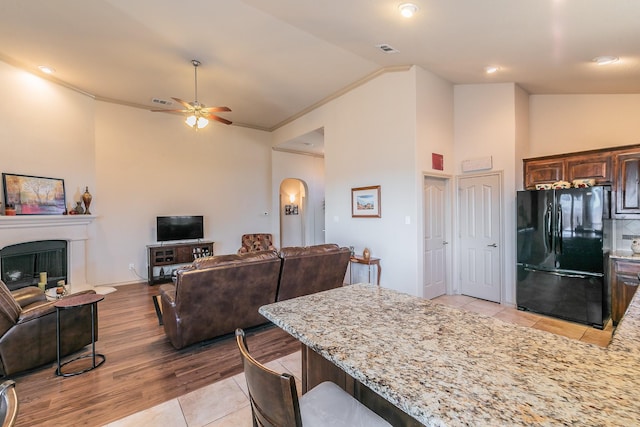 kitchen featuring arched walkways, open floor plan, a fireplace, and freestanding refrigerator