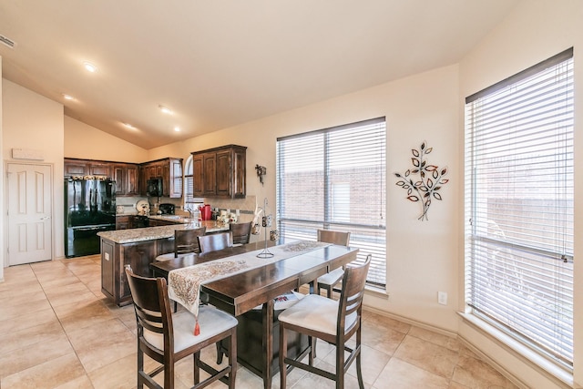 dining space with vaulted ceiling, light tile patterned flooring, baseboards, and visible vents