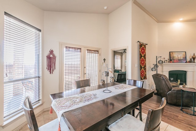 dining area featuring light tile patterned floors, french doors, a high ceiling, and a fireplace