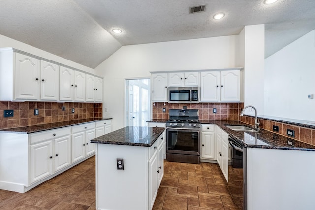 kitchen with tasteful backsplash, visible vents, dark stone counters, stainless steel appliances, and a sink