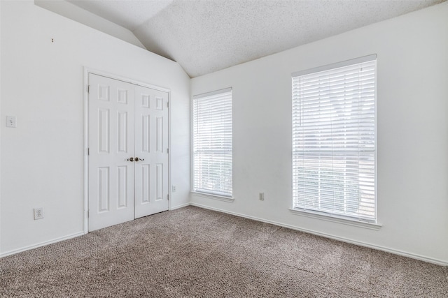 unfurnished bedroom featuring lofted ceiling, carpet, a closet, and a textured ceiling