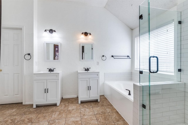bathroom featuring a shower stall, a garden tub, lofted ceiling, two vanities, and a sink