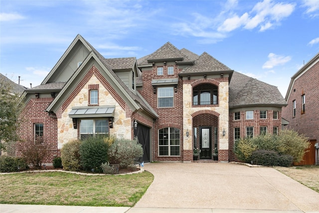 view of front of home with a balcony, driveway, roof with shingles, stone siding, and brick siding