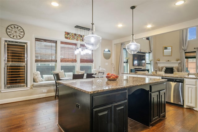 kitchen with dark wood-type flooring, stainless steel dishwasher, open floor plan, a center island, and dark cabinets